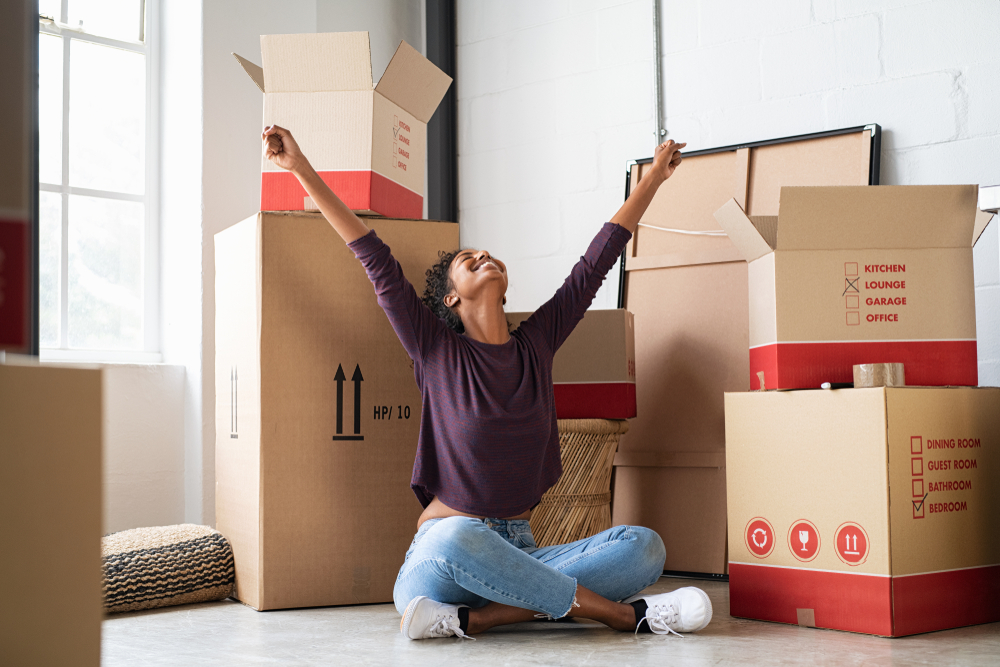 Happy,Young,Woman,Sitting,In,New,Apartment,And,Raising,Arms