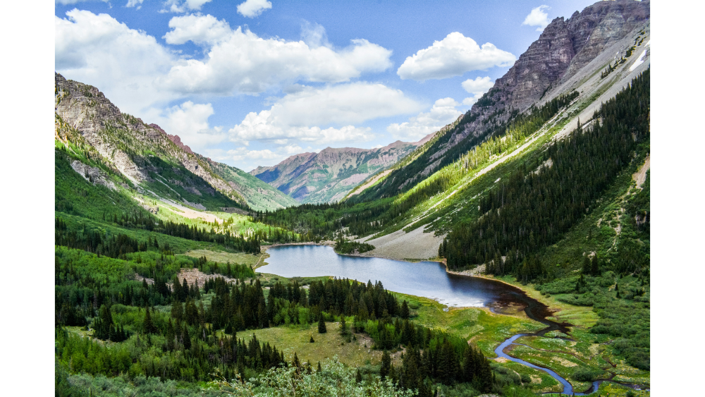 Scenic mountain valley with a lake and forested hillsides in Aspen, Colorado.