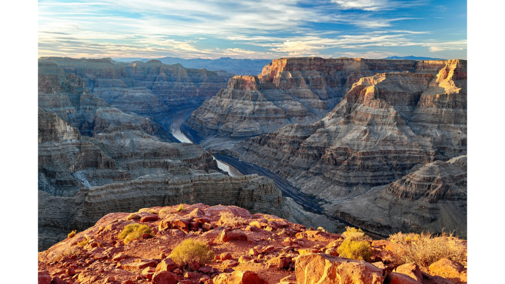 Sweeping view of the Grand Canyon with dramatic cliffs, deep gorges, and a winding river below.