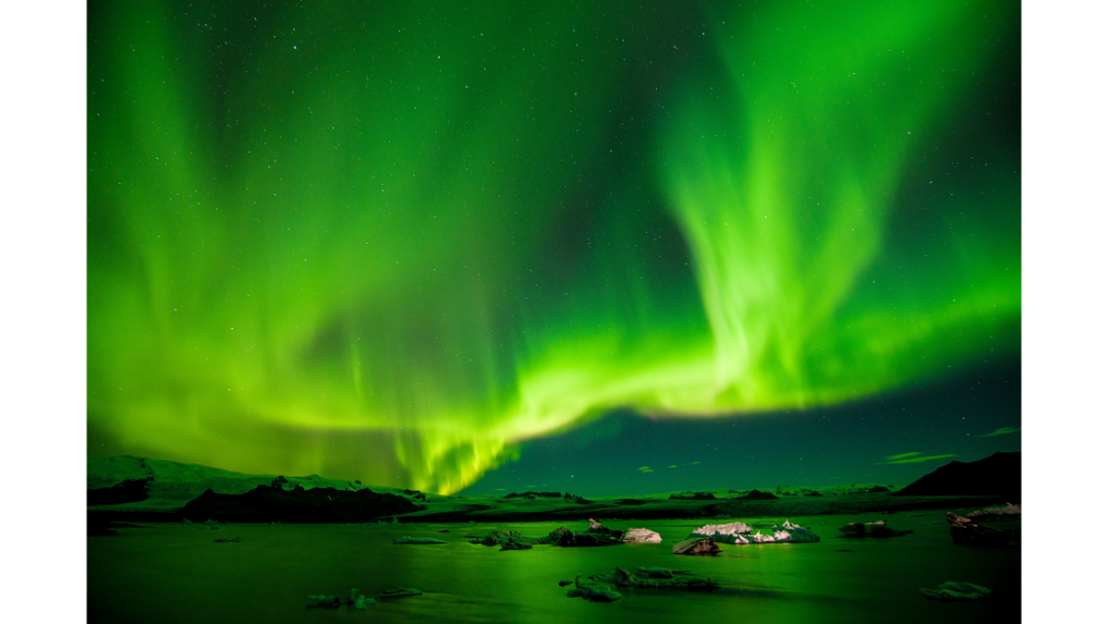 Bright green northern lights dancing across the night sky over a frozen Arctic landscape.