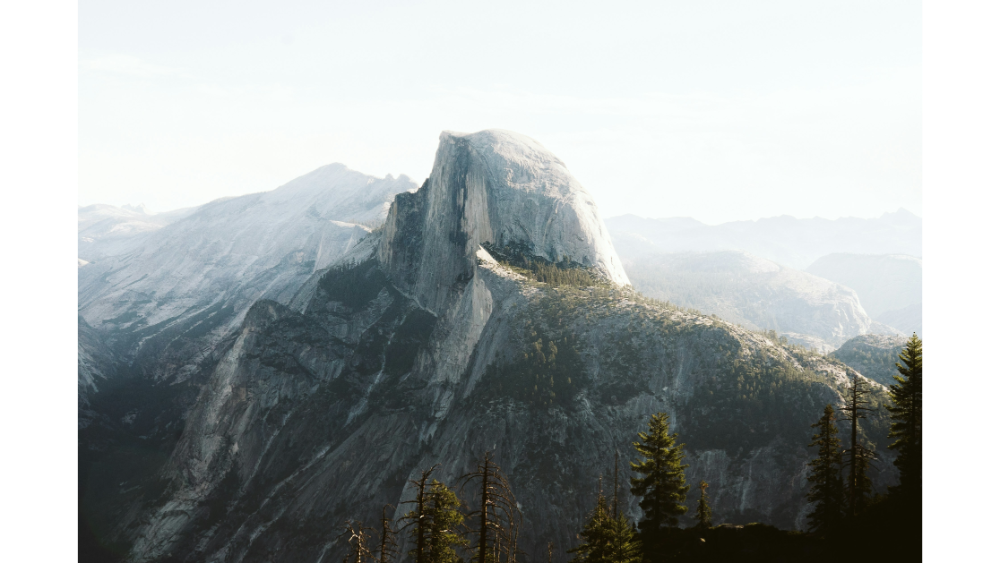 Iconic view of Half Dome surrounded by rugged granite peaks and forested valleys in Yosemite National Park.