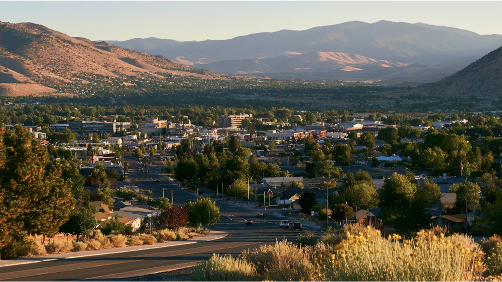 A view across Carson City, Nevada, showing downtown streets, residential areas, and the Sierra Nevada foothills surrounding the high-desert valley.