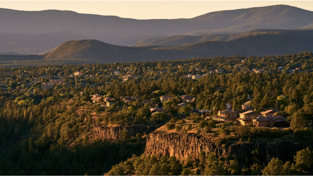 A residential neighborhood in Los Alamos, New Mexico, with detached homes, ponderosa pine trees, and the distinctive terrain of the Pajarito Plateau.