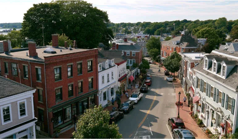 A walkable East Greenwich neighborhood with historic storefronts, traditional buildings, and a view toward the waterfront.