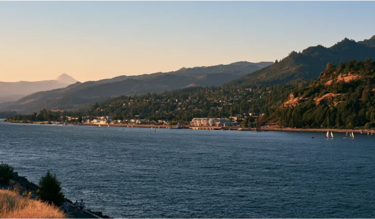 Hood River, Oregon, with the Columbia River, waterfront recreation, green hills, and Mount Hood rising in the distance.