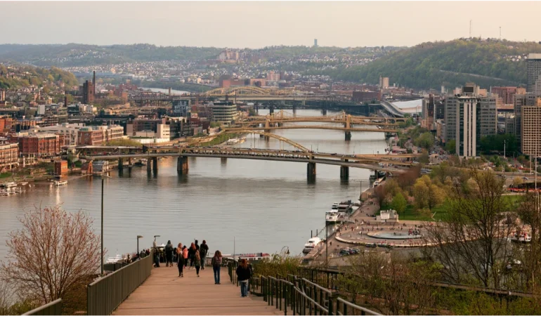 Pittsburgh neighborhood street with a university campus building, a healthcare facility, and public transit serving local residents.
