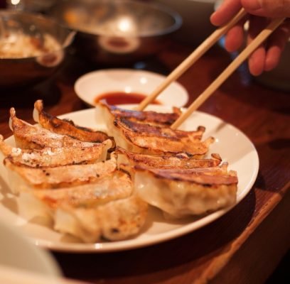 Crispy,Pan-fried,Japanese,Gyoza,Dumplings,On,A,Brown,Table,,With